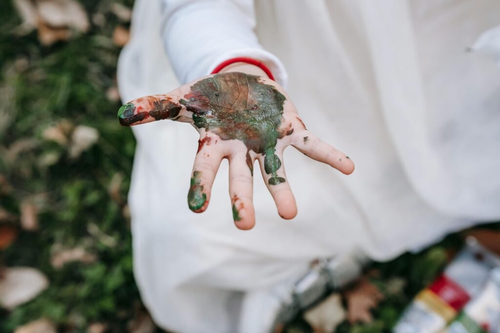 homeschooling, A child's hand covered in paint during outdoor playtime, capturing creativity and exploration.