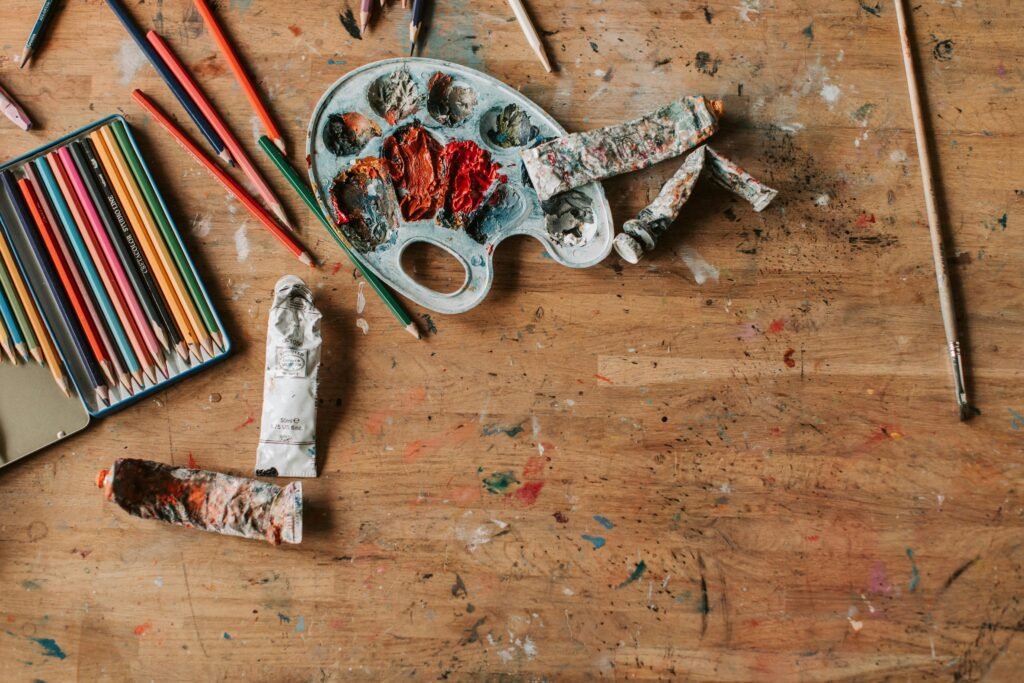 Vibrant colored pencils and paint palette create a creative, artistic setting.